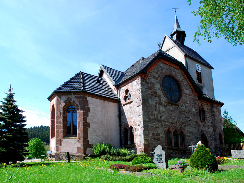 Steinkirche mit kleinem Turm vor grüner Wiese